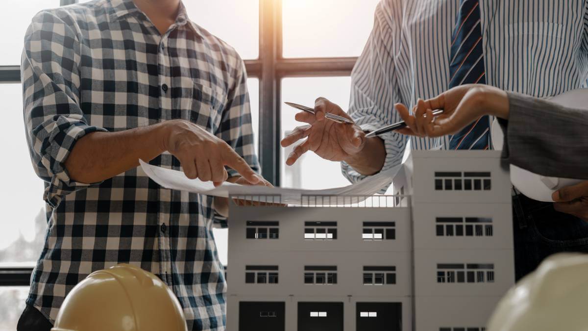 Two Men Looking At Building Model and Papers